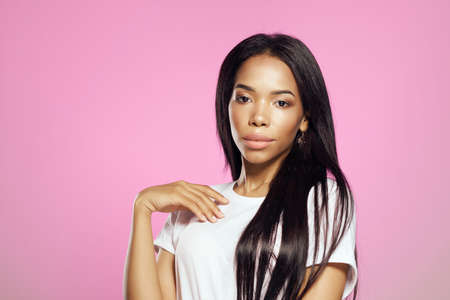 Woman in white t-shirt hairstyle cosmetics studio posing pink backgroundの写真素材