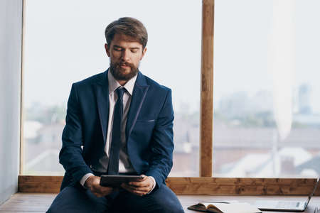 The man in a suit near the window with a laptop technologyの写真素材