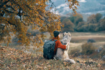 woman hiker with a backpack walks the dog in the mountains in natureの写真素材
