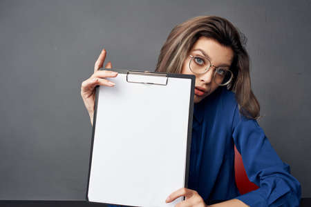 business woman with glasses sits at the table while holding Copy Spaceの写真素材