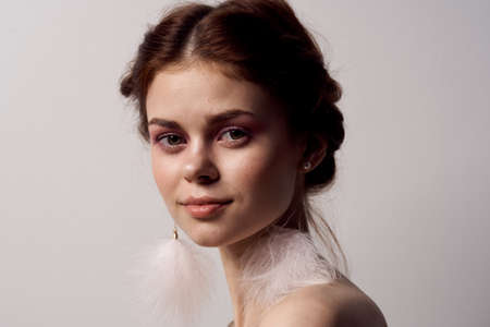 woman with bare shoulders bright makeup fluffy earrings fashion light backgroundの写真素材
