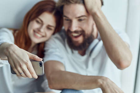 Man and woman sitting on the windowsill romance joy technologyの写真素材