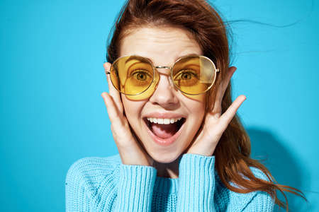 beautiful woman in fashionable glasses blue background