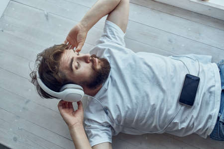 cute man lying on the windowsill wearing headphones Lifestyleの写真素材