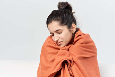 woman hiding with a blanket at home treatment cold infectionの写真素材