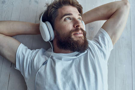 bearded man lying on the windowsill wearing headphones Lifestyleの写真素材