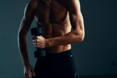a man with a pumped up press workout with dumbbells exercises dark backgroundの写真素材