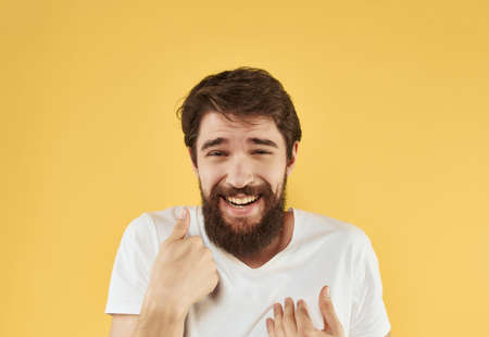 emotional man with a beard in a white t-shirt gestures with his handsの写真素材