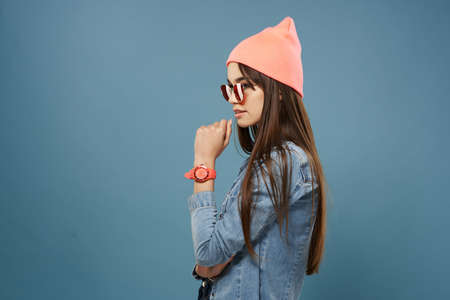 woman in pink hat sunglasses denim jacket hipster blue backgroundの写真素材