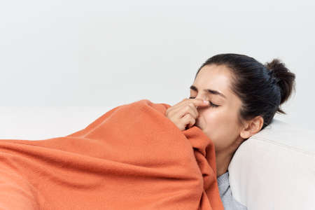 woman lies on the bed covered with a blanket cold treatmentの写真素材