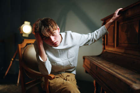 guy sitting near the piano posing studio spotlightの写真素材