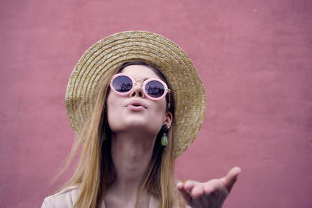 woman on the street wearing hat and glasses pink wall city trip