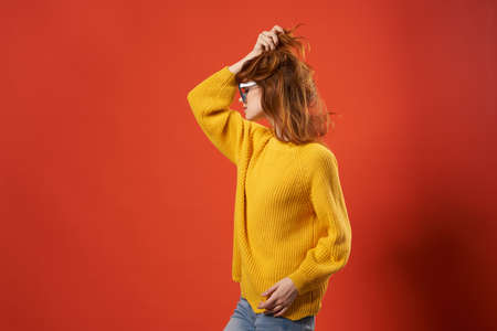 pretty woman in yellow sweater fashion glasses red backgroundの写真素材