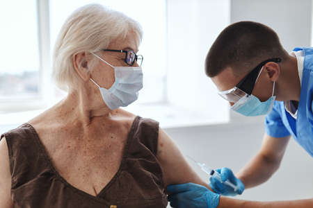 elderly woman in medical mask vaccinating at hospital doctor passport