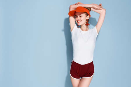 woman in white t-shirt red cap fashion summer style posing blue backgroundの写真素材