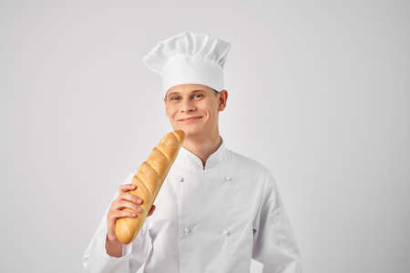 a man in chefs clothes with a baguette in the hands of a gourmet restaurantsの写真素材
