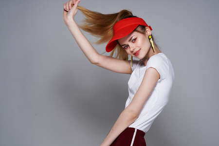 cheerful girl in a red cap holding her hair posing summer styleの写真素材