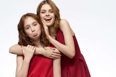 funny mom and daughter hugs red dresses fashion light backgroundの写真素材