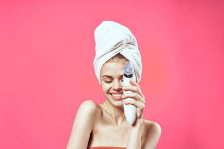 woman with bare shoulders with a towel on her head cleaning the skinの写真素材
