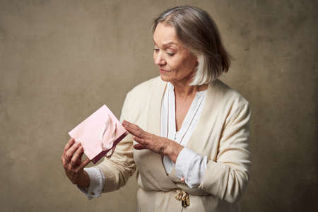 elderly woman in a dressing gown with a gift in her hands birthday careの写真素材