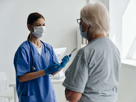 female nurse in a medical mask communicates with a patient in the hospital safety immunity  passportの写真素材