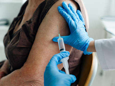 Nurse gives an injection to the shoulder of an elderly Patient close-up vaccines passportの写真素材