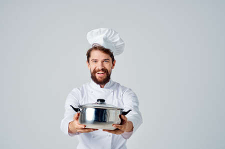 Cheerful chef with saucepan in hands kitchen cooking light backgroundの写真素材