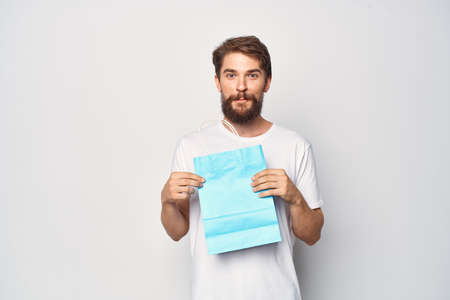man in white t-shirt blue package shopping light background