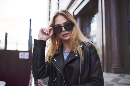 pretty woman in leather jacket walking down the streetの写真素材