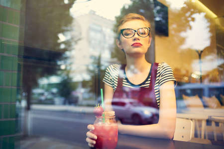 woman with short hair sits at a table in a cafe cocktail vacationの写真素材