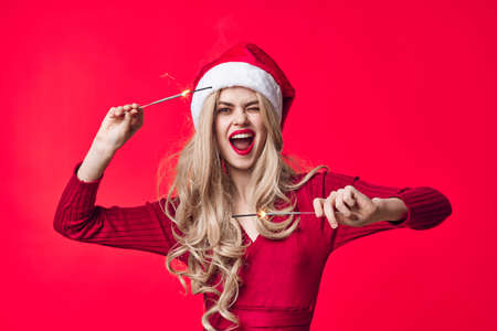 merry woman in santa hat sparklers christmas red backgroundの写真素材