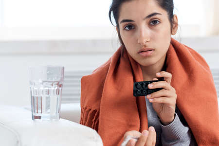 sick woman sitting at home medication treatmentの写真素材