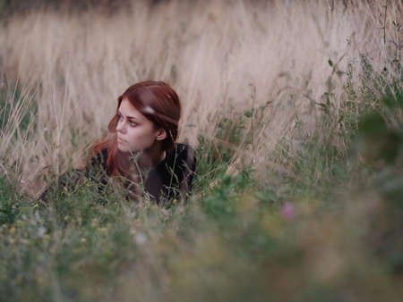red-haired woman lies on the grass in the field nature fresh air summerの写真素材