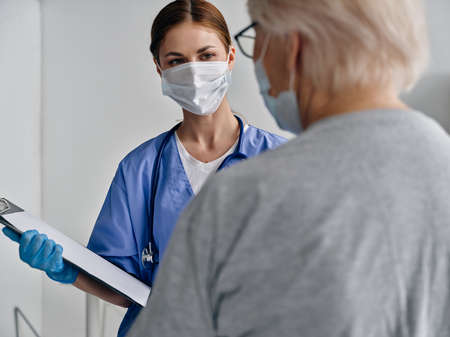 nurse otoscope from documents medical gloves mask patient elderly womanの写真素材