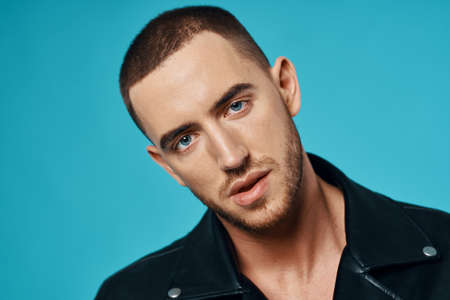 handsome man short haired leather jacket close-up blue backgroundの写真素材