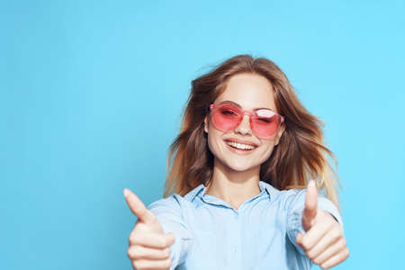 pretty blonde in pink glasses posing studio blue backgroundの写真素材