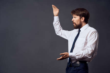 The man in a suit in a white shirt pulls the tie dark backgroundの写真素材