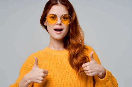 pretty woman in a yellow sweater fashion glasses light background
