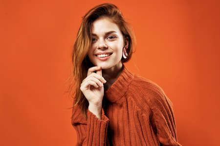 red-haired woman in a red sweater earrings jewelry close-upの写真素材