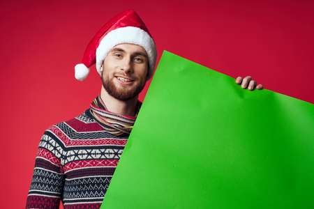 emotional man in a santa hat holding a banner holiday red backgroundの写真素材
