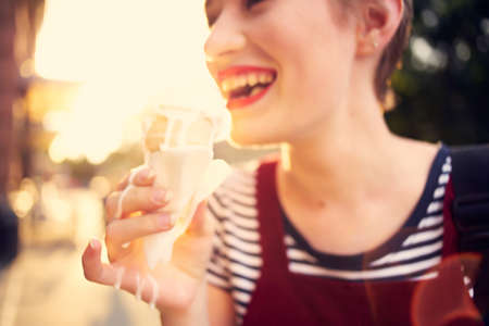 cheerful woman on the street eating ice cream walk summerの写真素材