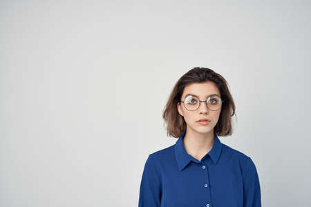 woman in blue shirt wearing glasses fashion cropped view light backgroundの写真素材