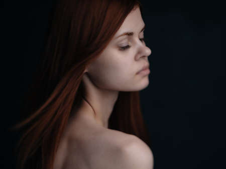 red-haired woman naked shoulders dark background glamorの写真素材