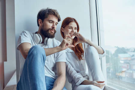 a young couple sitting on the windowsill romance joy