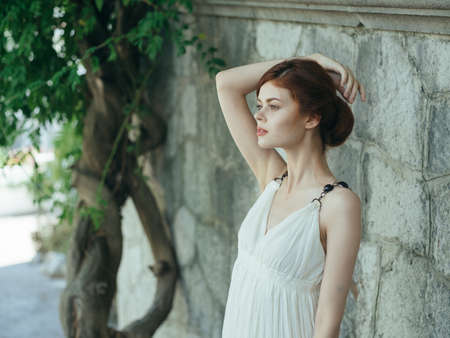 Woman in white dress near tree basing stone wall Greeceの写真素材