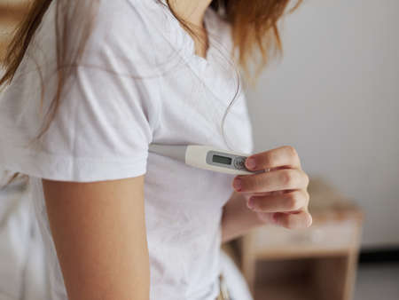 woman in white t-shirt hold thermometer armpit health temperature