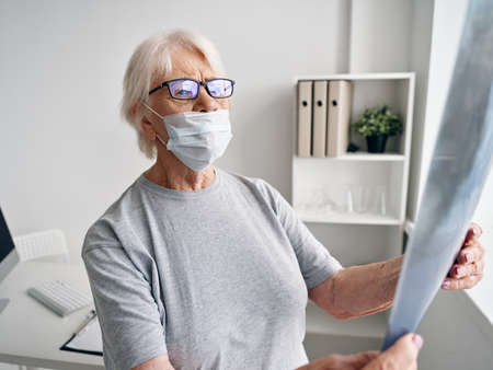 elderly woman retired with x-ray in hospital near window covid-19 passportの写真素材