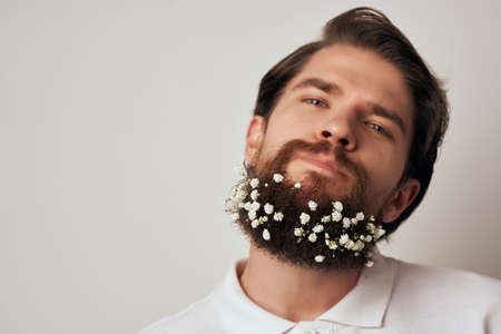 portrait of a man posing flowers in a beard fashion close-upの写真素材