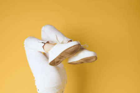 inverted legs in white sneakers fashion modern style yellow backgroundの写真素材