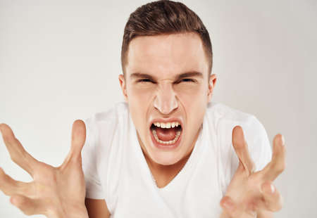 angry man in white t-shirt emotion displeasure close-upの写真素材